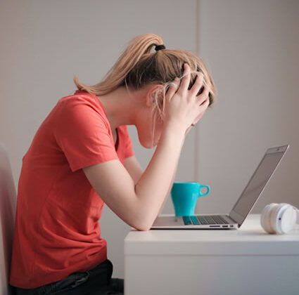 woman front of computer holding her head